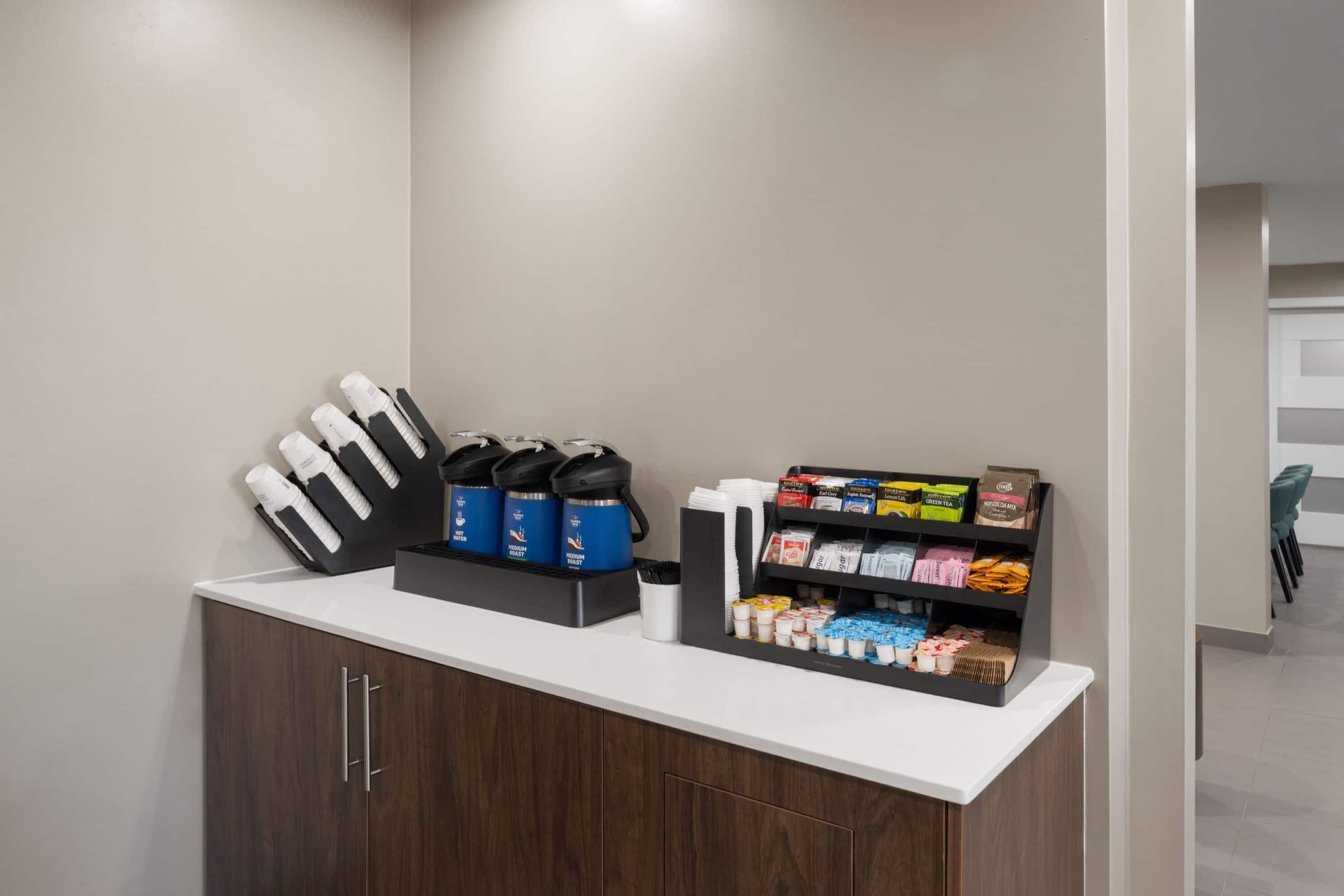 A reception area with a counter, coffee machines, and a snack display.