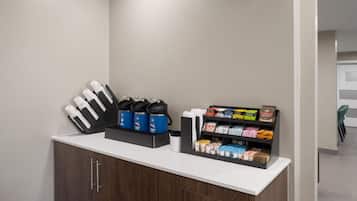 A reception area with a counter, coffee machines, and a snack display.