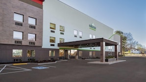 Un hôtel moderne doté d’une entrée couverte, de nombreuses fenêtres et d’un parking.