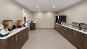 Une cuisine moderne dotée d’un long comptoir, d’appareils électroménagers intégrés et d’un design épuré et minimaliste.