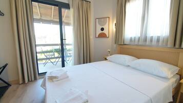 Ein Hotelzimmer mit einem großen Bett, einem Fenster mit Vorhängen, einem Wandbild und Blick auf einen Außenbereich.