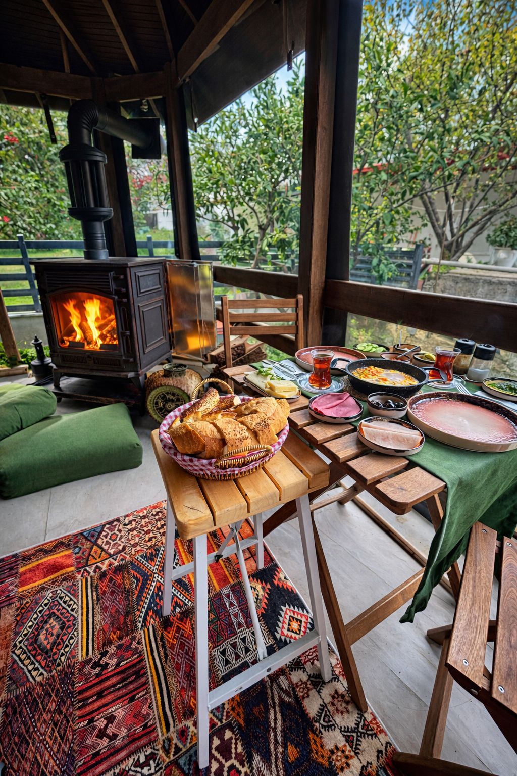 A cozy outdoor dining area with a wood-burning stove, a variety of dishes, and a colorful rug.