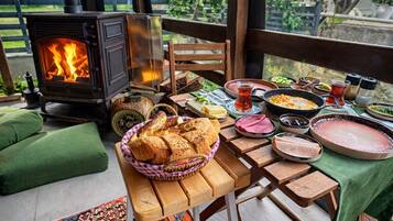 A cozy outdoor dining area with a wood-burning stove, a variety of dishes, and a colorful rug.