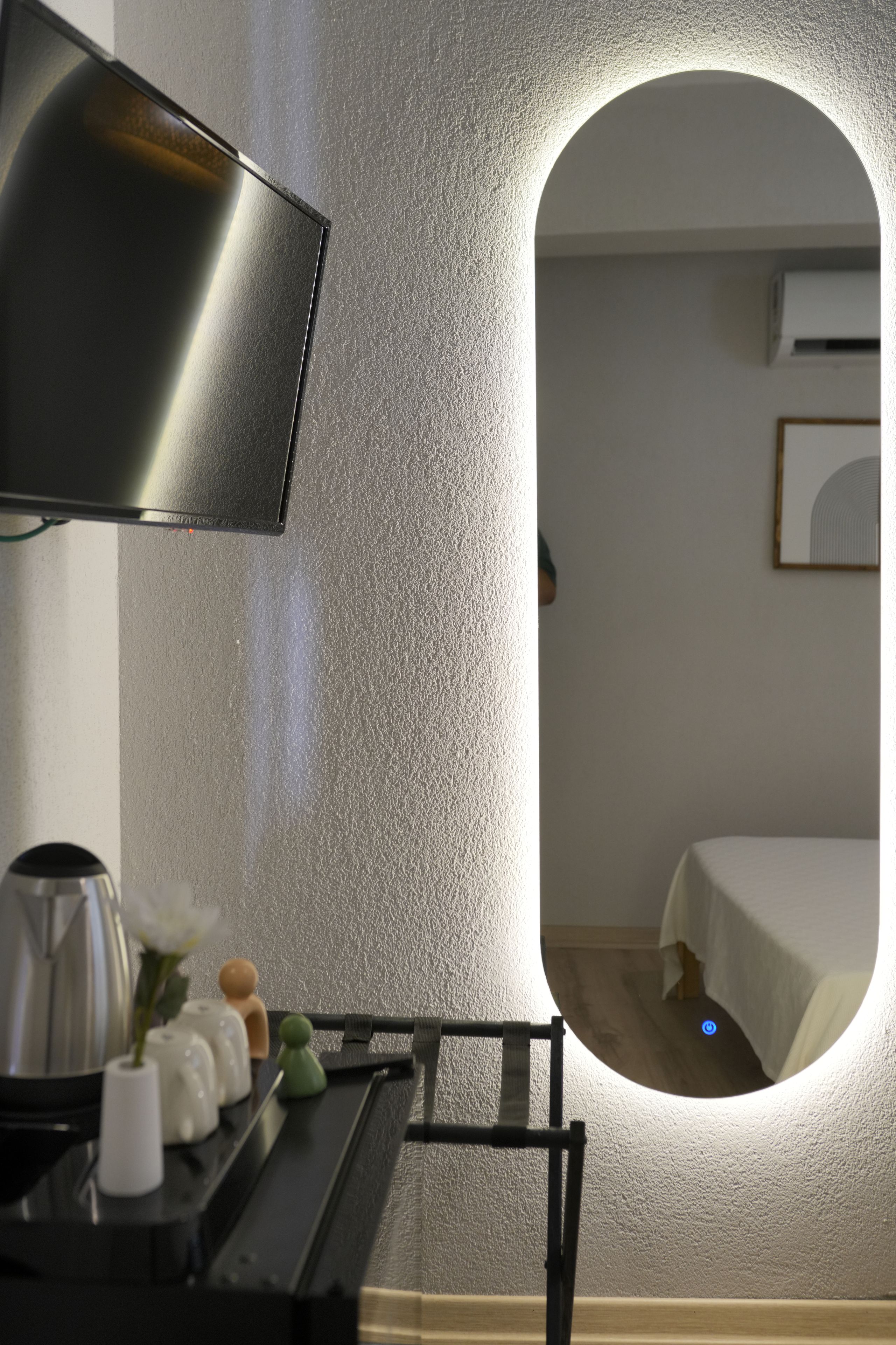 Habitación de hotel moderna con un espejo grande, un televisor de pantalla plana y una cama.