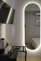 Habitación de hotel moderna con un espejo grande, un televisor de pantalla plana y una cama.