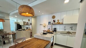 Una cocina moderna con una mesa de comedor de madera, armarios blancos y una lámpara colgante.