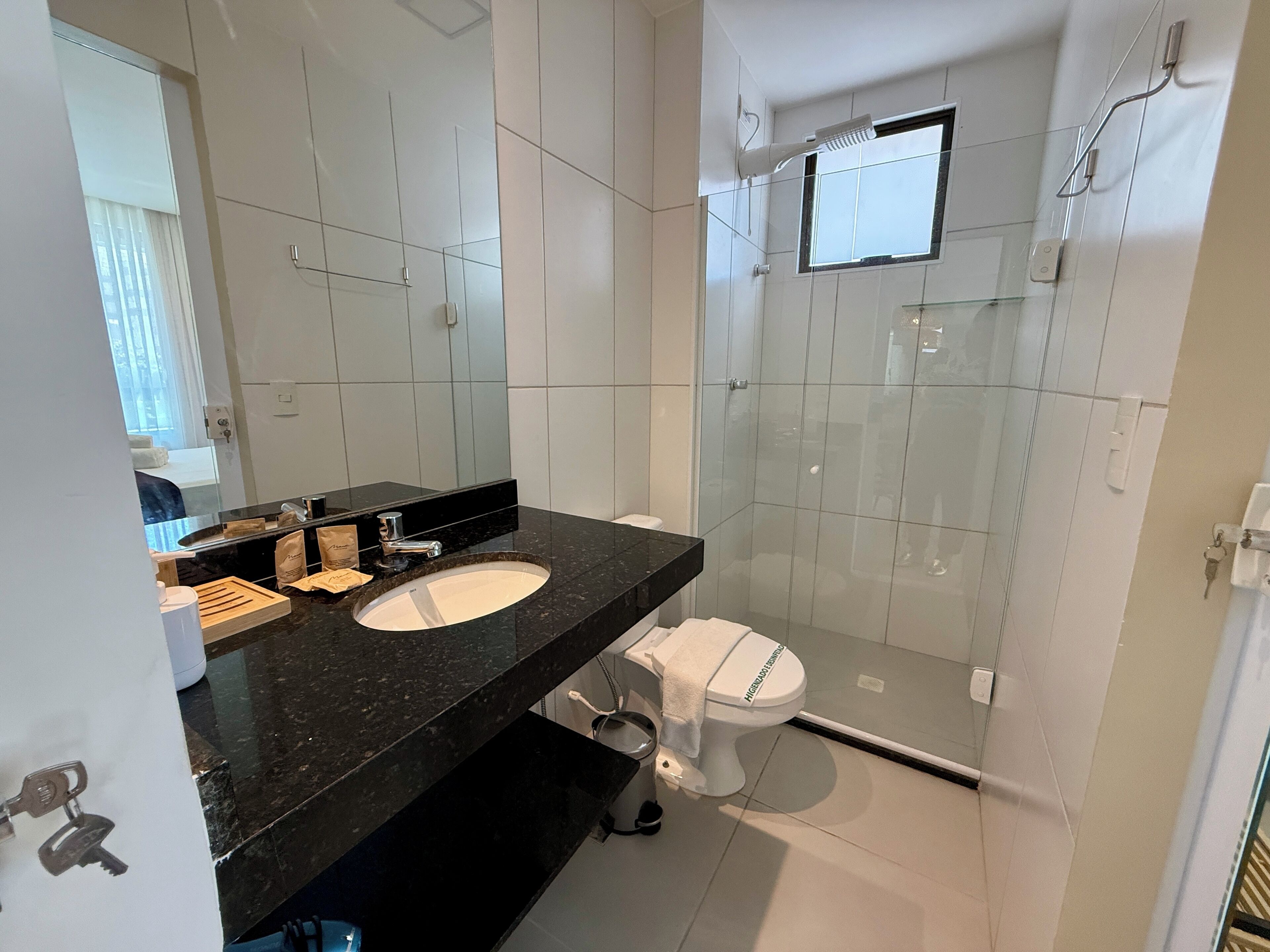A modern bathroom with a black marble countertop, a white sink, and a toilet.