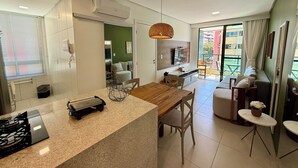 Una cocina moderna con encimera de granito, estufa integrada y comedor con mesa y sillas de madera.