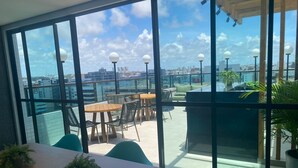 Una terraza moderna en la azotea con paredes de vidrio, mobiliario exterior y vistas al horizonte de la ciudad.