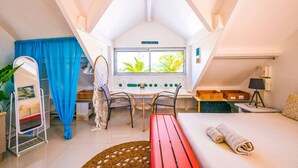 Una habitación acogedora con una cama, un escritorio, una silla, un ventanal con vistas a zonas verdes y una mesita con una lámpara.