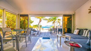Un salón moderno con vistas a la playa, un sofá, una mesa de centro y un comedor con sillas y una mesa.