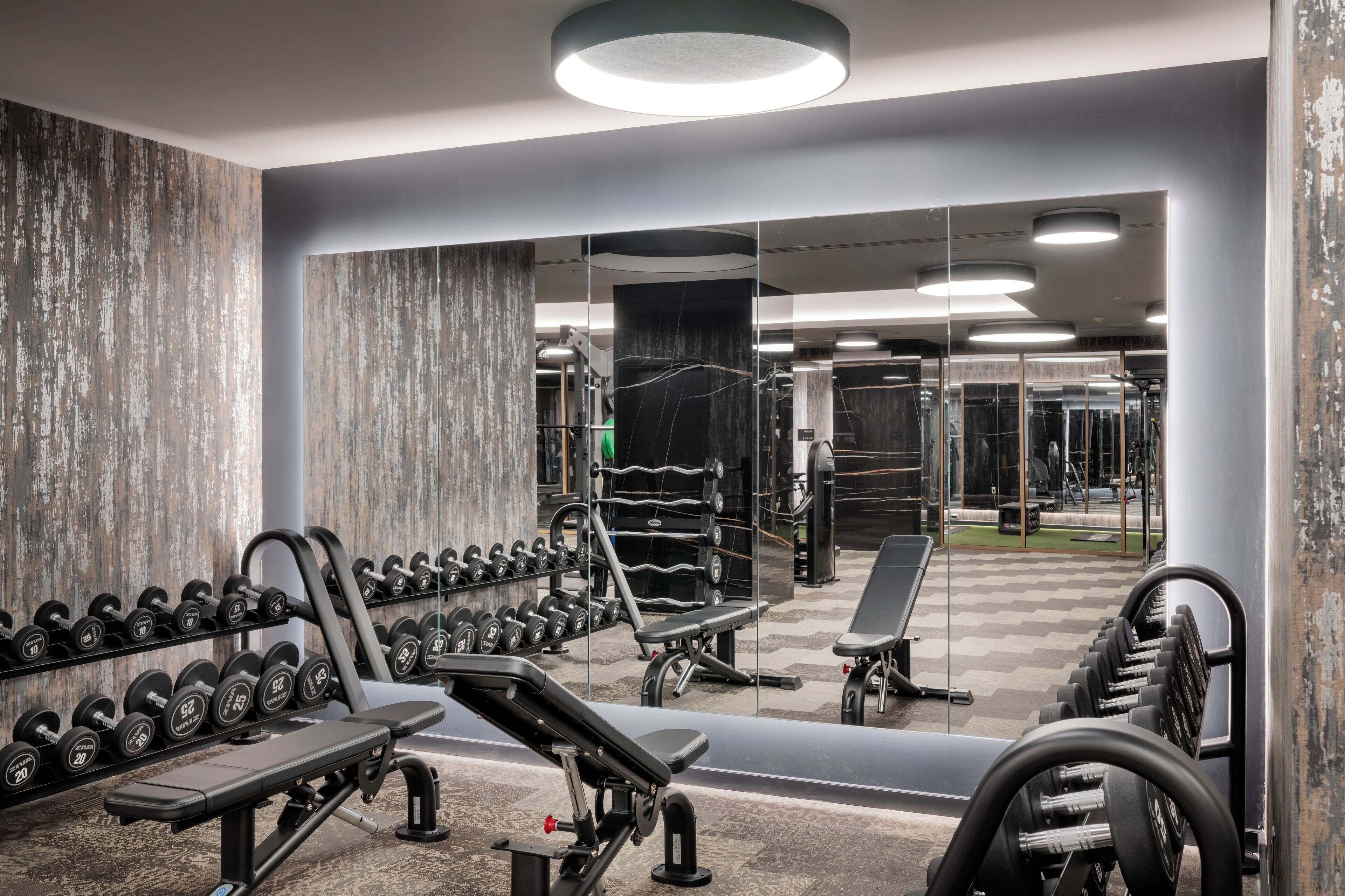A gym with weightlifting equipment, benches, and dumbbells.