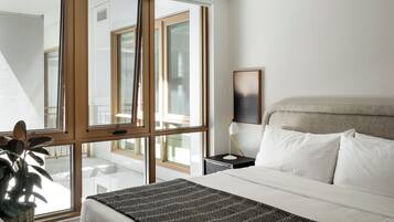 A hotel room with a bed, bedside lamp, and a view through a large window.