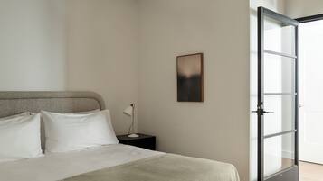 A bedroom with a bed, a nightstand, a lamp, a framed picture, and a sliding glass door.