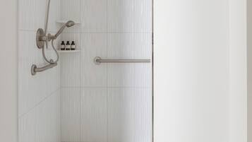 A walk-in shower with a handheld showerhead, a handheld shower attachment, and a towel bar.