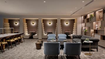 Un'area lounge moderna con un tavolo lungo, diversi divani e un tavolino.