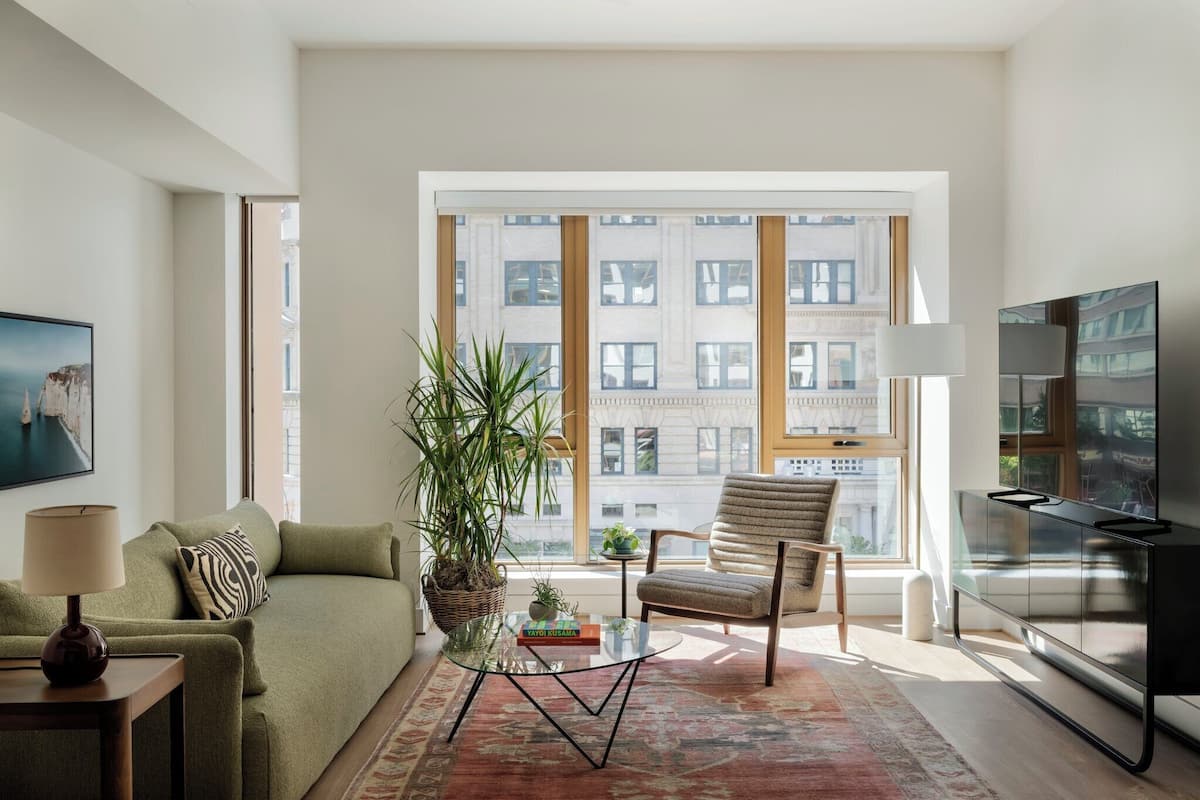 A modern living room with a sofa, armchair, and a glass coffee table.