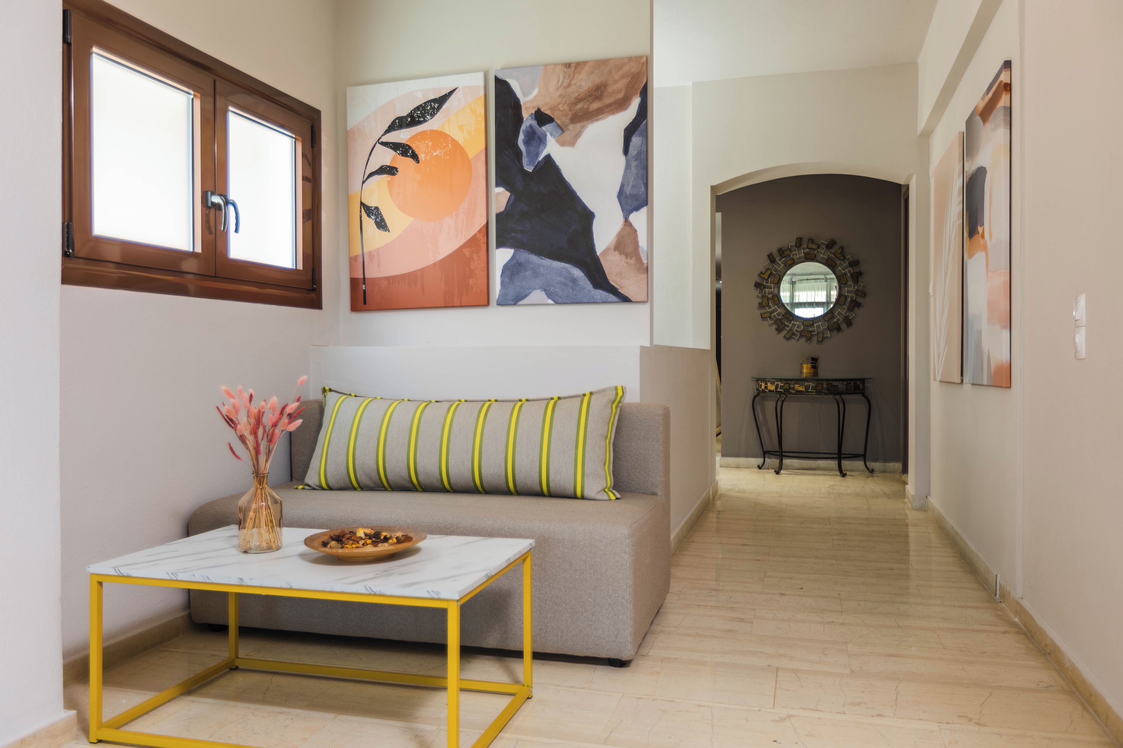Un salon avec un canapé, une table basse et des œuvres d’art accrochées aux murs.