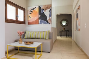 Una sala de estar con sofá, una mesa de centro y obras de arte en las paredes.