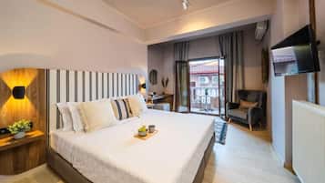 Un dormitorio de hotel con una cama grande, mesitas de noche, televisión y un balcón con una silla.