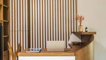 A reception desk with a laptop, a vase with flowers, and a magazine.
