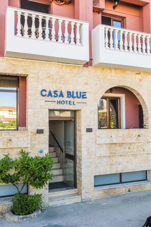 A hotel named "Casa Blue" with a stone facade, a balcony with white balustrades, and a visible entrance.
