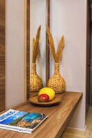 Una mesa de madera con dos jarrones tejidos, un plato con una manzana y un limón, y una revista.