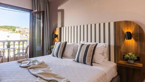 A hotel room with a large bed, a view of the city, and a balcony with outdoor seating. - Casa Blue Hotel (Skiathos)
