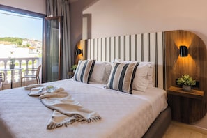 A hotel room with a large bed, a view of the city, and a balcony with outdoor seating. - Casa Blue Hotel (Skiathos)