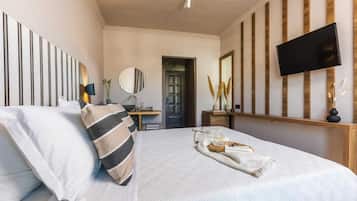 Un dormitorio con una cama, un televisor de pantalla plana montado en la pared, una mesita de noche con lámpara y una puerta que da a otra habitación.