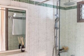 Une salle de bain dotée d’une douche à parois de verre, d’un porte-serviettes et d’une fenêtre donnant sur l’extérieur.