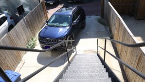 A vehicle parked at the top of a set of outdoor stairs leading to a building.