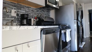 A modern kitchen with a stainless steel stove, a microwave, and a refrigerator.