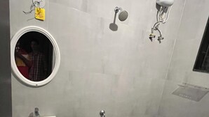 A bathroom with a sink, mirror, toilet, and a red bucket. - Velvet vista (Tirupporur)