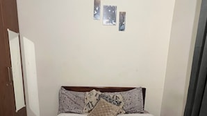 A bedroom with a wooden bed frame, a white mattress, and patterned pillows. There are three wall-mounted pictures above the bed. - Velvet vista (Tirupporur)