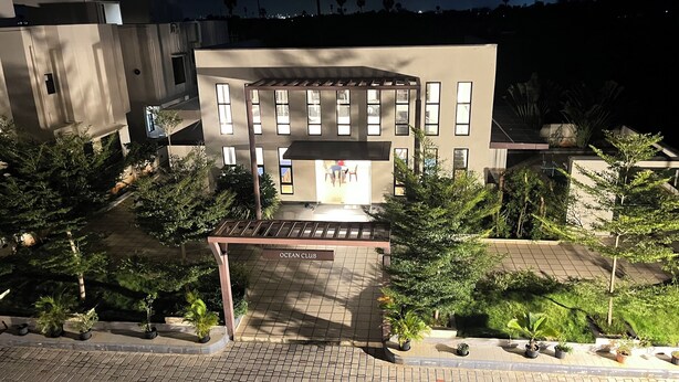 A modern building with a central open area, surrounded by potted plants and a tiled entrance. - Velvet vista (Tirupporur)