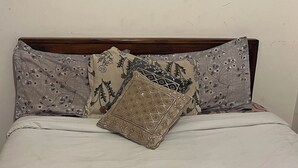 A bed with a wooden headboard, a white mattress, and three patterned pillows. - Velvet vista (Tirupporur)
