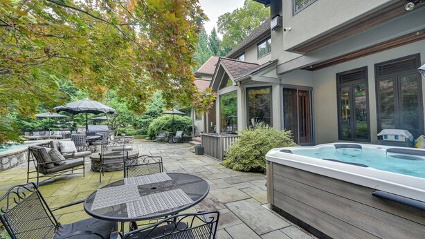 Un patio con mobiliario exterior, un jacuzzi y una piscina.