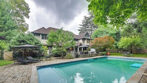 Un patio trasero con piscina, sillas de descanso y una zona de estar al aire libre.
