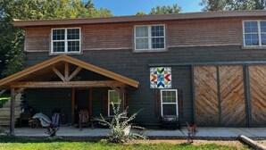 A two-story log cabin with a covered porch, a garage, and a colorful quilt hanging on the wall. - 3-bedrooms, 2 bathrooms upstairs cabin in charming French Lick with AC (French Lick)