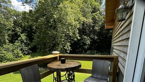 A wooden deck with two chairs and a table, overlooking a grassy yard and trees. - 3-bedrooms, 2 bathrooms upstairs cabin in charming French Lick with AC (French Lick)