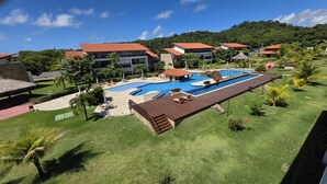 A resort with a large swimming pool, multiple buildings with red roofs, and lush greenery. - Club Meridional Carneiros 01PS  byLP (Tamandaré)