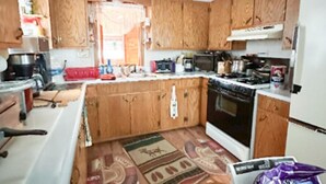 Una cocina compacta con armarios de madera, estufa, refrigerador y cafetera.