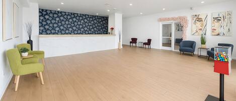 A spacious lobby with a wooden floor, a reception desk, and several seating areas.