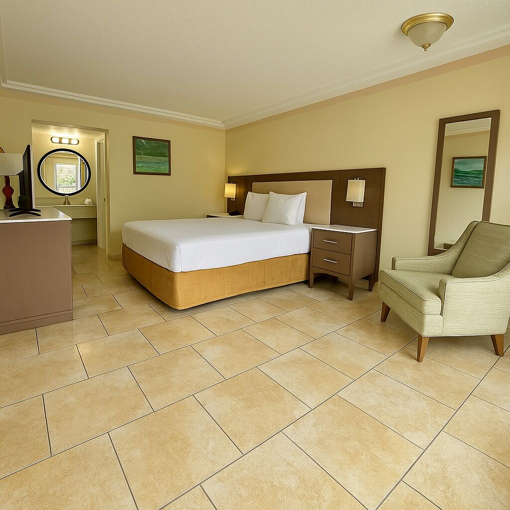 A hotel room with a large bed, a bedside table, a chair, and a desk with a lamp.