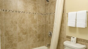 A bathroom with a bathtub, toilet, and shower curtain. - Unno Boutique Hotel  (Kissimmee)