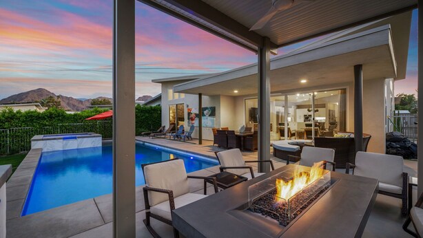 A modern outdoor patio with a pool, fire pit, and comfortable seating.