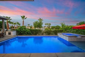 A swimming pool with a view of palm trees and a sunset. - Modern Desert Retreat | Pool, Spa, EV Charger, Near Tennis Garden (Indian Wells)