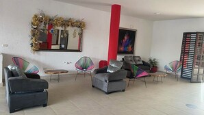 Un hall d’entrée spacieux, doté de sièges modernes, d’un grand miroir et d’un pilier rouge.