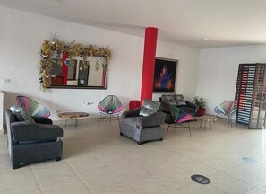 Un vestíbulo amplio con asientos modernos, un espejo grande y un pilar rojo.